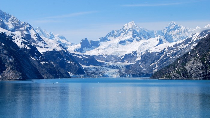 Snow-capped mountains and a glacier overlooking a calm blue lake
