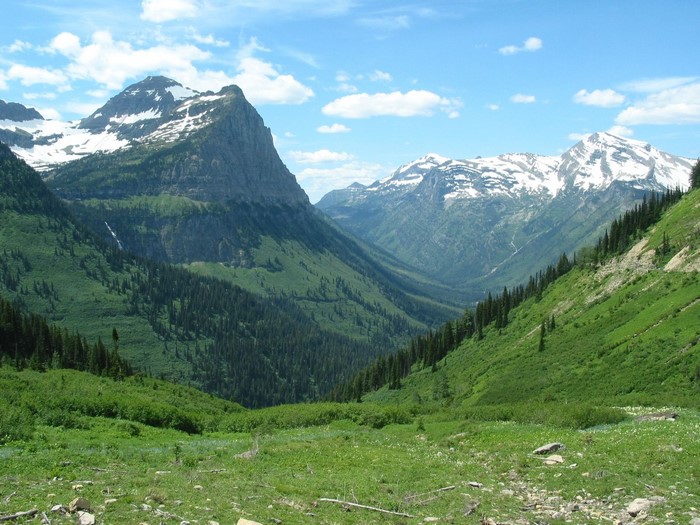 Snow-capped mountains and green valley under a blue sky
