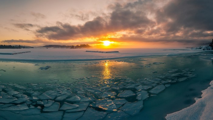Frozen bay at sunrise with ice floes and clouds