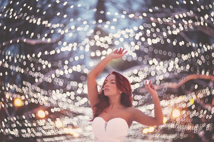 Woman in white dress with red hair dancing among lights