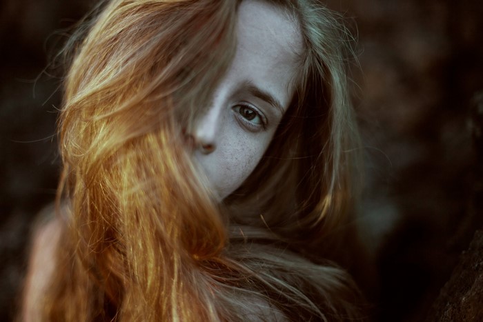 Portrait of a young woman with red hair covering her face