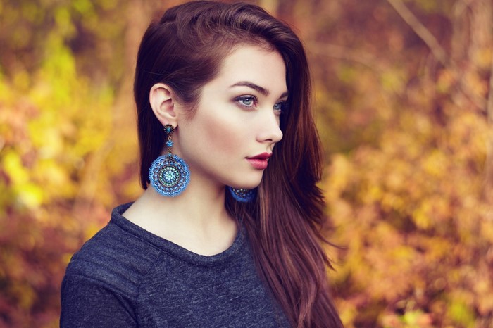 Woman with large blue earrings in autumn