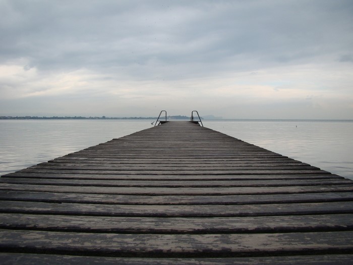 Wooden pier extending into a calm lake under a cloudy sky