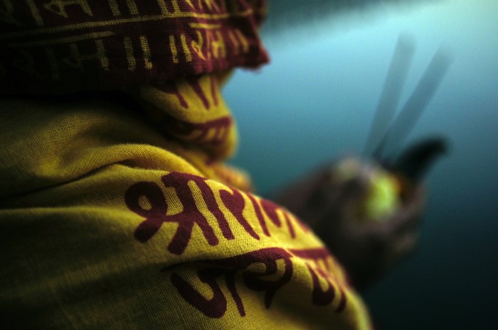 Person in yellow religious clothing holding incense sticks