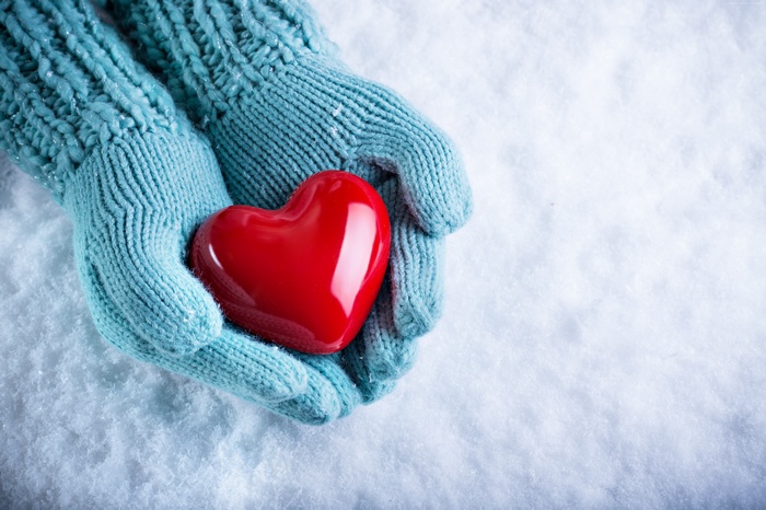Hands in Gloves Holding Red Heart in Snow