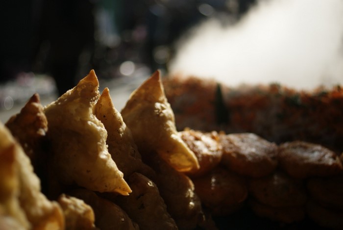 Close-up of fried samosas and other snacks with steam