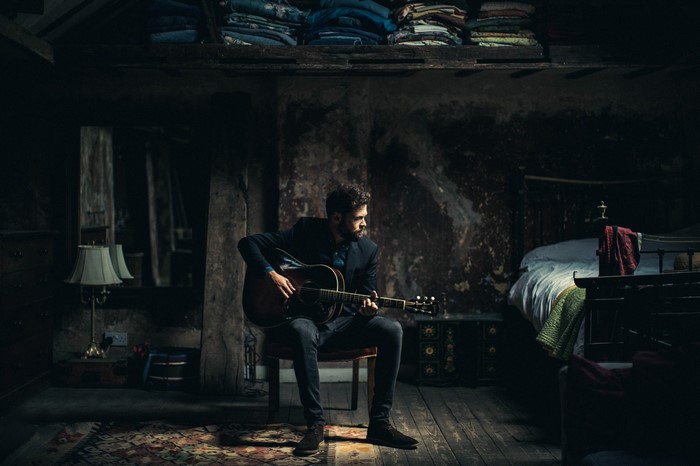Man playing guitar in a dark room