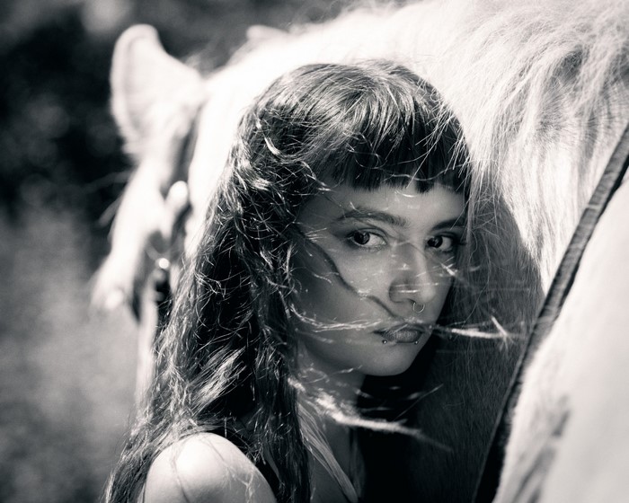 Woman with piercings next to a horse