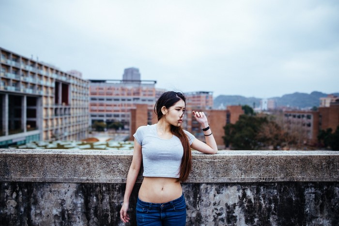 Asian woman in crop top and jeans on rooftop