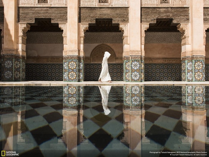 Person in white robe walking by a reflecting pool in Morocco
