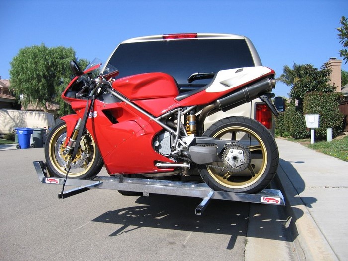 Red Ducati motorcycle on a trailer attached to a car