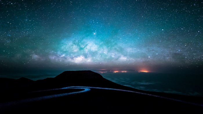 Night sky with Milky Way over mountains and city lights