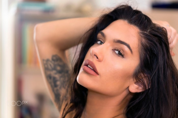 Woman with tattoo and hands on head