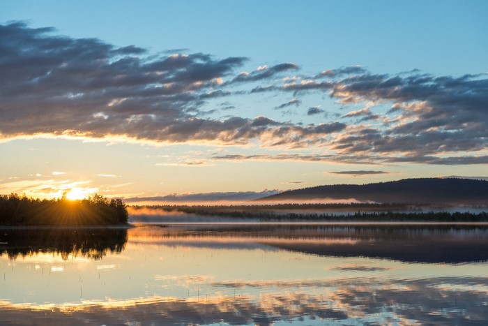 Sunrise over a misty lake with sun rays
