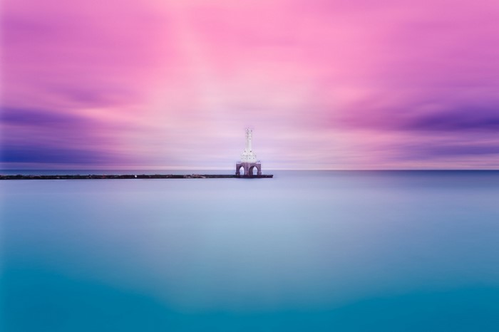 Lighthouse on a pier at sunset with colorful sky
