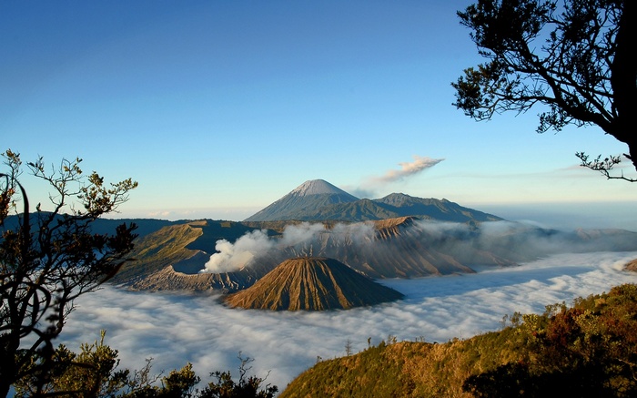 Volcanoes shrouded in mist under a clear blue sky