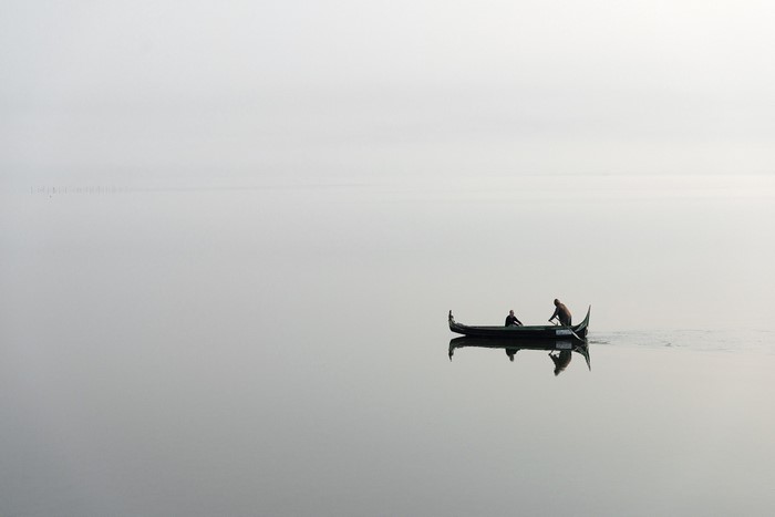 Two people in a boat on a foggy lake
