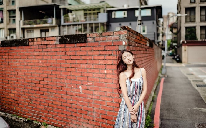 Woman leaning against a brick wall in an urban setting