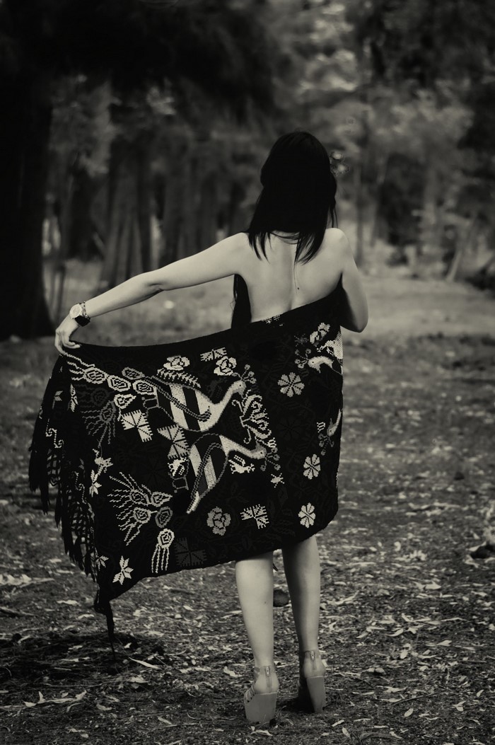 Woman in patterned shawl in a forest