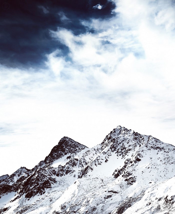Snow-covered mountains under a dramatic sky