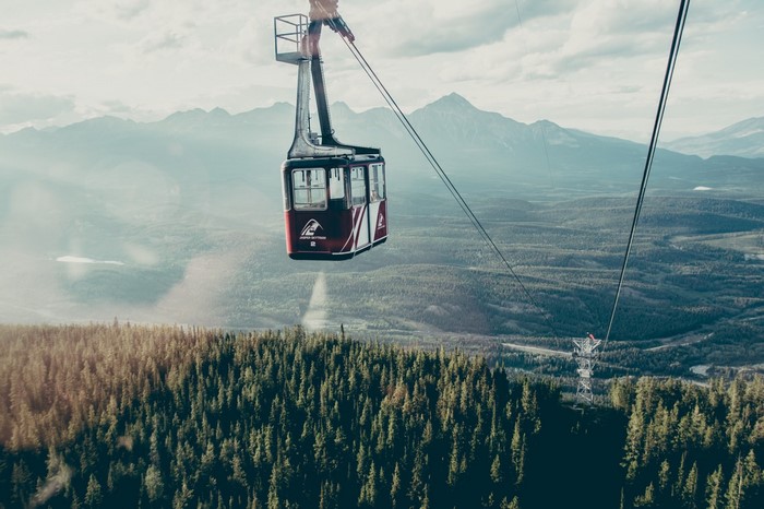 Cable car over a forest with mountains in the background