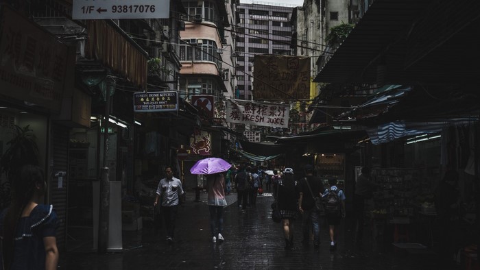 People walking in a dark, rainy street market