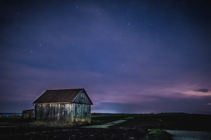 Wooden barn under a starry night sky