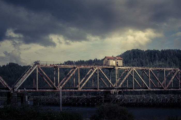 Abandoned railway bridge with small shacks and forest