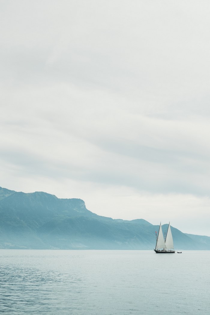 Sailboat on a calm lake with mountains in the background