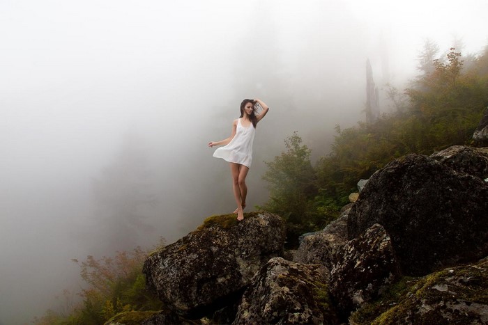 Woman in white dress on rocks in mist