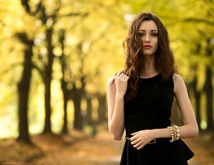 Woman in black dress with red lipstick in autumn park