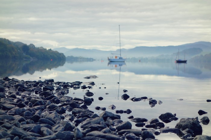 Boats on a misty lake with rocky shore