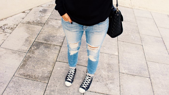 Woman wearing ripped jeans and black high-top sneakers
