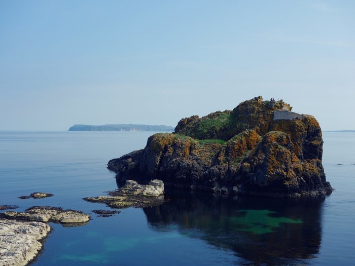 Rocky island in the sea with a distant coastline