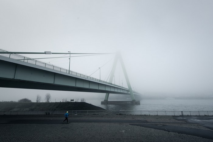 Person running under a cable-stayed bridge in fog