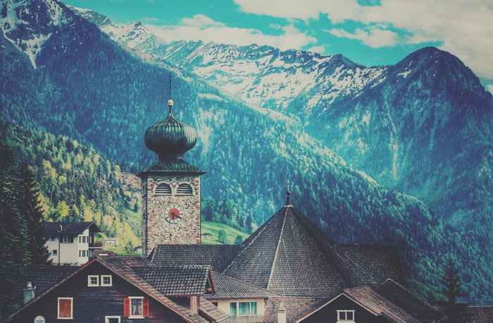 Village church tower with Alps mountains in the background
