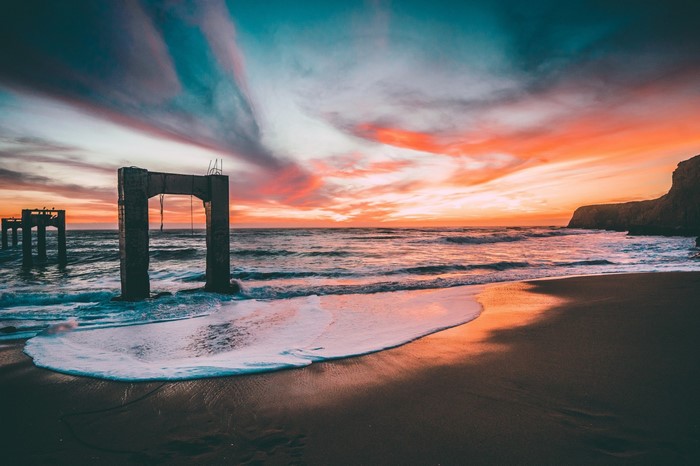 Concrete ruins on a beach at sunset