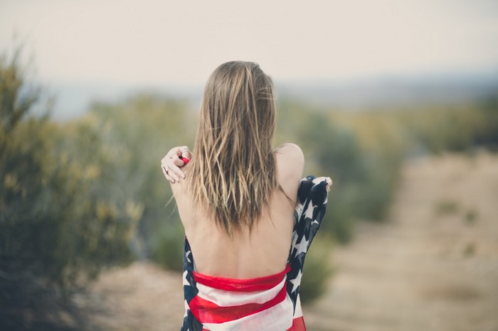 Woman wrapped in American flag outdoors