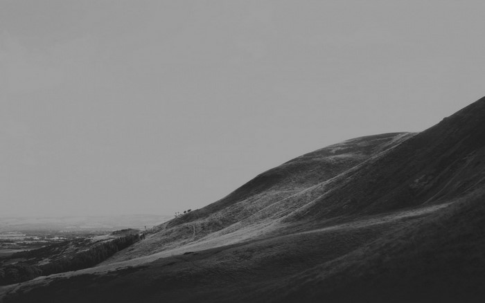 Monochrome landscape of rolling hills and a distant town