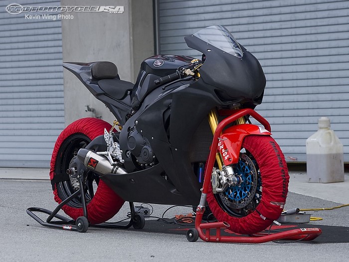 Black Honda sport motorcycle with red tire warmers