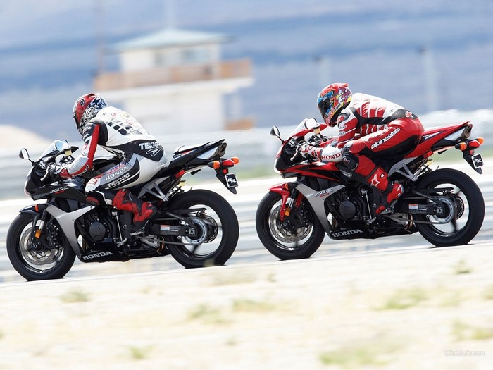 Two Honda motorcycles racing on a track