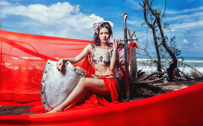 Fantasy girl with sword and shield on beach