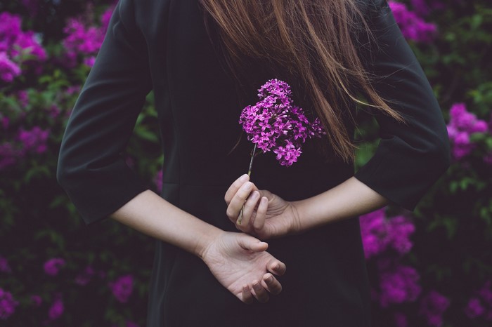 Woman in black dress holding purple flowers