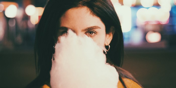 Woman holding cotton candy in front of her face