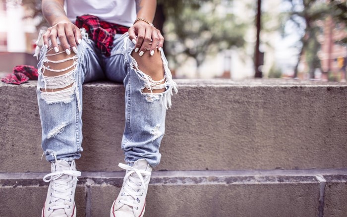 Woman wearing ripped jeans and white sneakers