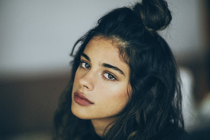 Woman with dark hair in a bun, looking at the viewer