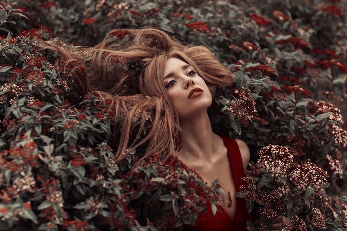 Woman with long hair lying in red flowers