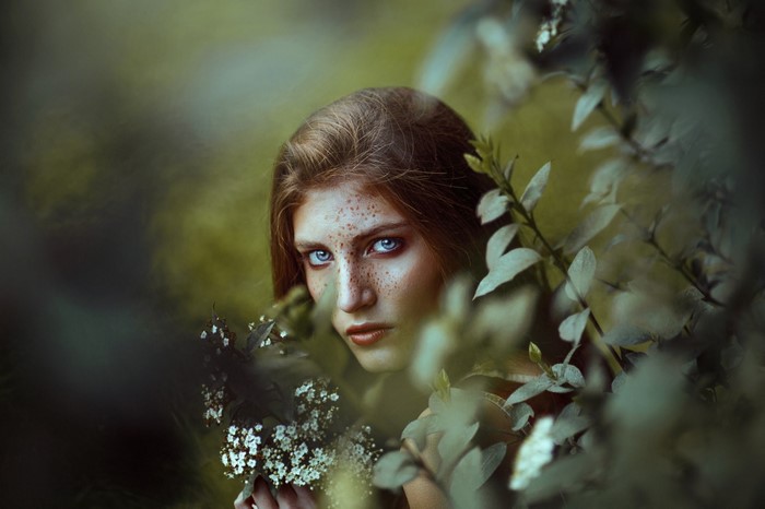 Woman with freckles and blue eyes in foliage