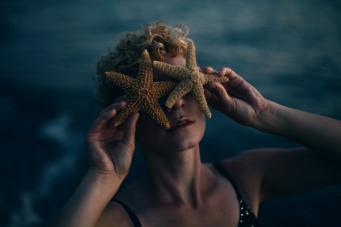 Woman holding starfish over her eyes