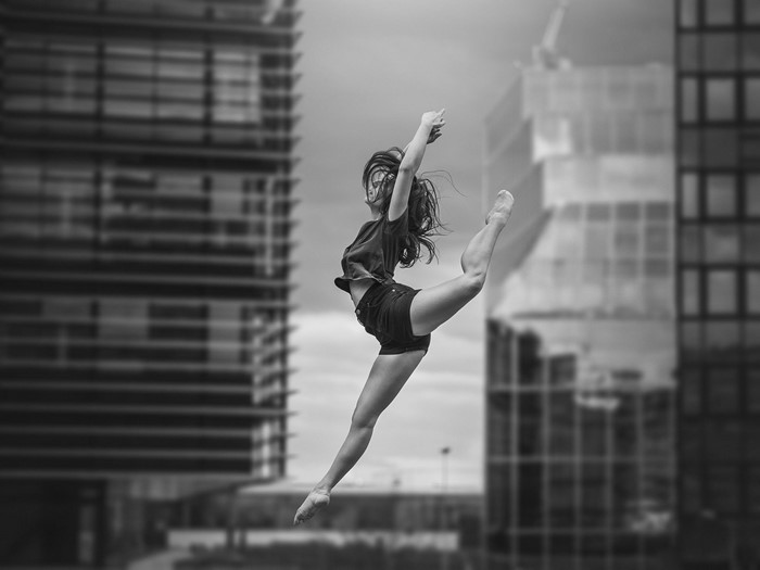 Woman performing ballet jump between buildings